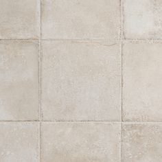 a white tile floor with different shades of gray and beige tiles on the bottom half