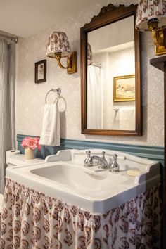 a white sink sitting under a bathroom mirror next to a shower curtain in a bathroom