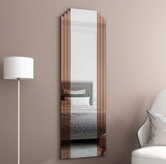 a large mirror sitting on top of a wall next to a white chair and lamp