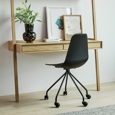 a black chair sitting in front of a desk with a potted plant on it