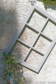 an open window sitting on the side of a building next to a planter with flowers growing in it