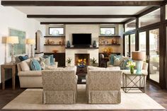 a living room filled with furniture and a flat screen tv mounted on the wall above a fireplace