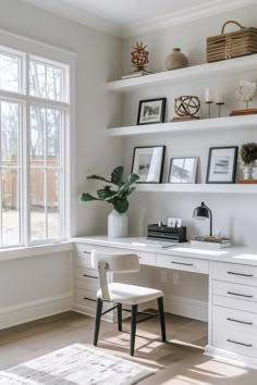 a white desk and chair in a room with shelves on the wall above it, near a window