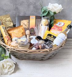 a wicker basket filled with lots of food and condiments next to a white rose