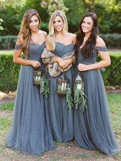 three beautiful women in long dresses standing next to each other with their arms around each other