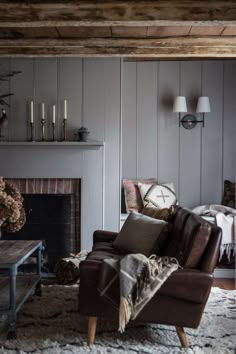 a living room filled with furniture and a fire place in front of a wooden wall