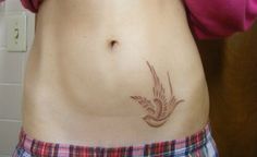 a woman's stomach with a bird tattoo on her belly and the bottom part of her body