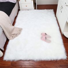 a white rug with pink slippers on the floor next to a dresser and bed