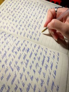 a person writing on a notebook with a pen