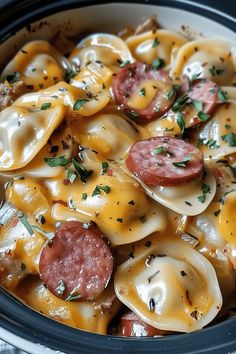 a crock pot filled with pasta, sausage and cheese covered in melted cheese sauce