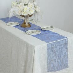 a vase with white flowers on top of a blue and white table cloth covered table