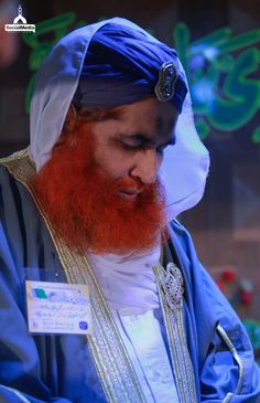 a man with a red beard wearing a blue turban is looking at his cell phone