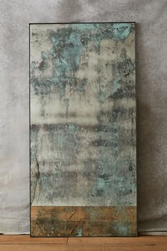 an abstract painting with blue and brown colors on a white wall next to a wooden floor