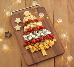 a wooden cutting board topped with cheese, tomatoes and star shaped appetizer pieces