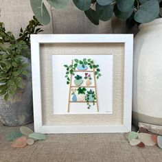 a white frame with some green plants in it and a potted plant next to it