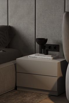 two books are stacked on top of each other in front of a bed with a gray headboard