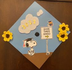 Graduation cap with snoopy walking towards a sign that says “good times ahead” with Woodstock. Felt cloud at the top reads 2022, and there are crochet sunflowers on the left and right corners of the cap. Charlie Brown Graduation Cap, Minimal Grad Cap Design, To Infinity And Beyond Graduation Cap, Garfield Graduation Cap, Gudetama Graduation Cap, Miffy Graduation Cap, Peanuts Graduation Cap, Snoopy Graduation Cap Designs, Minion Graduation Cap