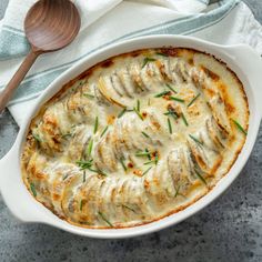 a casserole dish with meat and cheese in it next to a wooden spoon