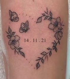 a heart shaped tattoo with flowers and leaves on the side of her leg, which reads date 11 11