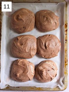 four chocolate donuts sitting on top of a baking sheet