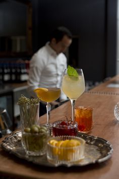 a man standing behind a bar filled with drinks