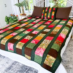 a bed with a green, red and brown quilt on it's headboard