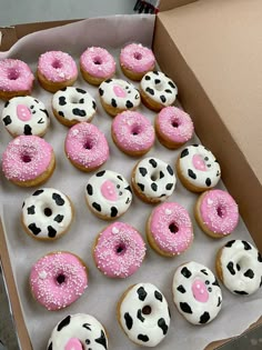 a box filled with lots of pink and white frosted sprinkle covered donuts