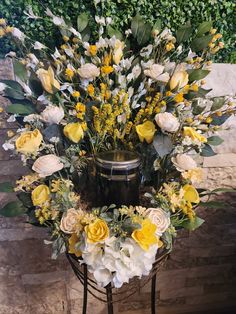 yellow and white flowers are arranged in a basket