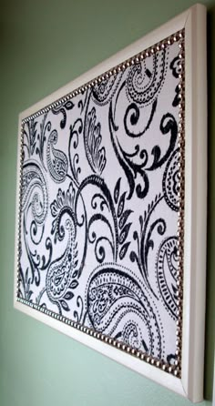 a painting hanging on the wall with black and white paisley designs in it's frame