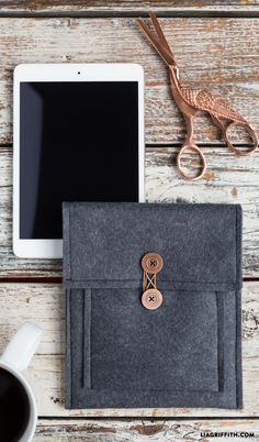 an ipad, tablet and some scissors on a wooden table with a cup of coffee