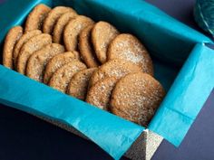 a blue box filled with cookies covered in powdered sugar on top of a table