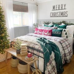 a bedroom decorated for christmas with plaid bedding and green throw pillows on the bed