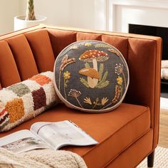 an orange couch with a decorative pillow on it and a magazine laying next to it