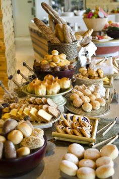 a table topped with lots of different types of breads and pastries next to each other