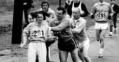 an old black and white photo of men running in a race with numbers on their shirts