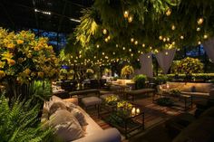 a room filled with lots of furniture and flowers on the ceiling, surrounded by greenery