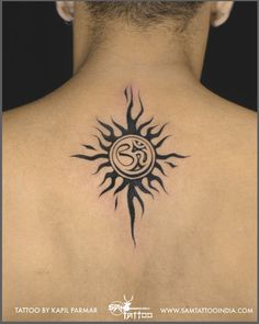 the back of a man's neck with a sun tattoo on his left side