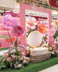 a display with pink flowers and mirrors in the grass at a shopping mall for women's day