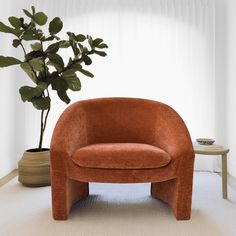 an orange chair sitting next to a potted plant in a room with white walls