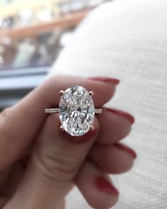 a close up of a person's hand holding a ring with a diamond in it