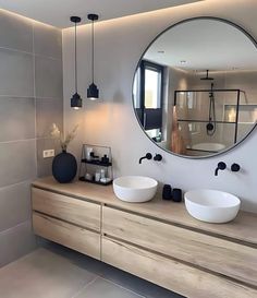 a bathroom with two sinks and a large round mirror on the wall above it's counter