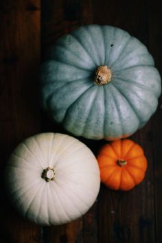 three pumpkins sitting on top of a wooden table