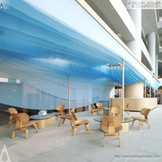 an empty lobby with chairs and tables in front of a large blue wave painted on the wall