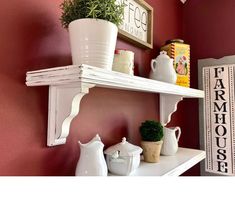 two white shelves with pots and plants on them in a red walled room next to a sign that says farmhouse