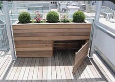 a wooden bench sitting on top of a deck next to a planter filled with potted plants