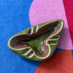 a green leaf shaped object sitting on top of a blue and pink carpeted floor