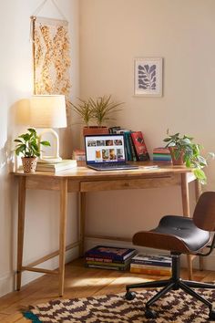 a wooden desk with a laptop on top of it next to a lamp and potted plant