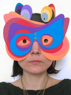 a woman wearing a mask made out of paper with different colored shapes on her face