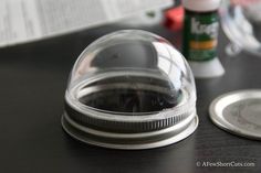 a plastic dome sitting on top of a table next to a silver plate and bottle