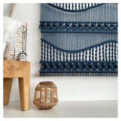 a woven wall hanging next to a wooden stool